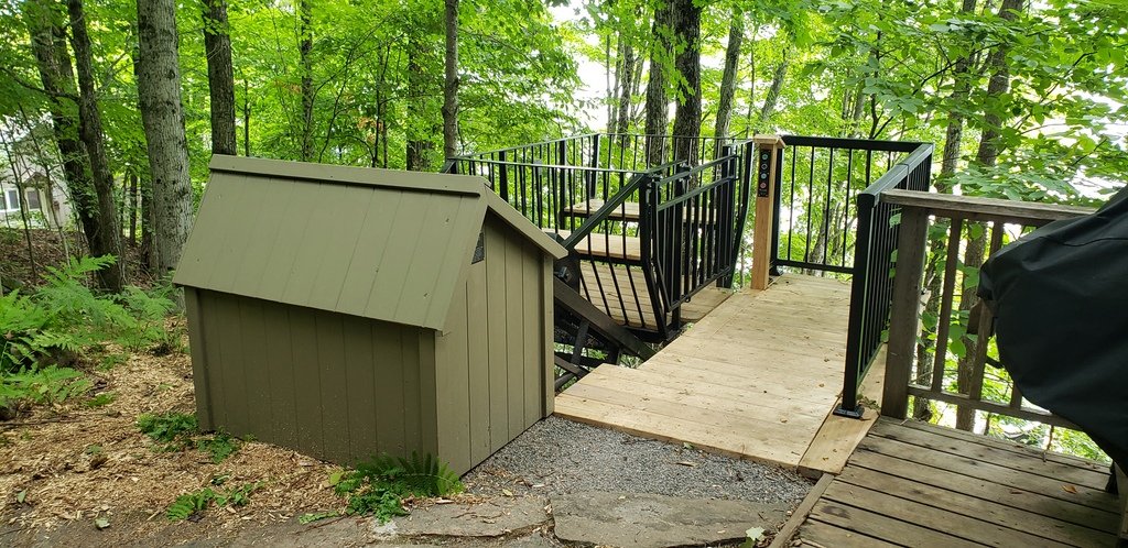 Their carpenter did a lovely job extending the existing platform, complete with new railings and a self-closing, self-latching gate, to form the upper-station platform. The motor house is colour-matched to an existing shed behind and to the left of the camera. The lift control panel sits on the far end of that shed, with all wiring buried to keep visual obstructions minimal.