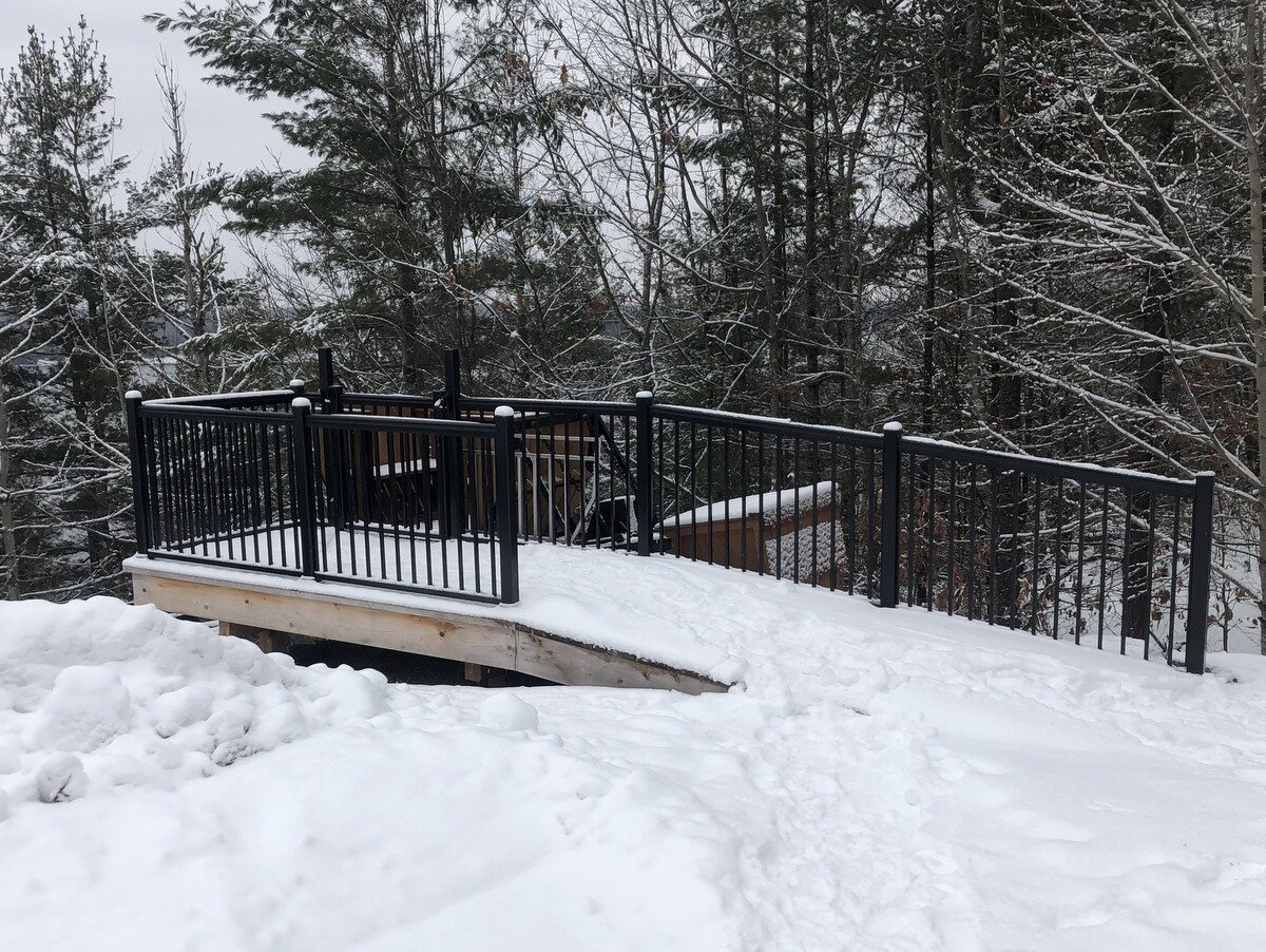 The upper station platform was built by Infinity Fine Homes. Access from the parking area and cottage is easy, and the lift makes quick work of moving people and supplies between cottage and water. The upper section of track runs at 11 degrees—the most gentle pitch we have ever built—and the change in angle to the lower section is 27 degrees, the largest transition we have built and the reason for our longest piece of curved track. The motor and winch sit in the housing at the top of the track, and the control panel is mounted on the back of a shed about 30 feet up the hill.