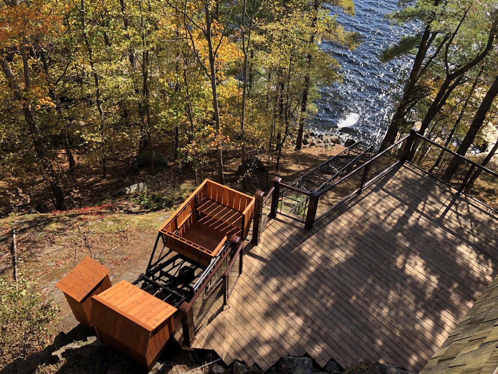 This overview, taken from an upper deck, shows how cleanly the lift fits into the deck. Shoreline Construction renewed the decking, Excel Enclosures provided the railings, and McMorran Electric ran the branch line to power the lift. We then integrated the lift control buttons and associated wiring into the gate posts. Because the top of the track is very close to the ground, we mounted the lift control panel in its own housing off to the side. With the station platform low to the ground, the owner opted not to interlock the gate. On two-pitch lifts we normally recommend interlocking both gates, but here the second pitch is short and there is a direct line of sight between stations, so interlocks were not essential.