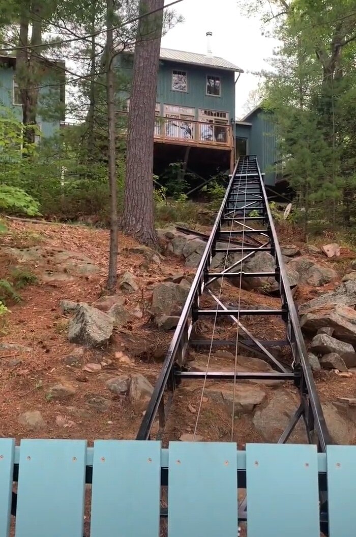 Looking up the track toward the cottage. The main living area is on the front-deck level, which makes the lift ideal for moving people and supplies the four storeys between dock and cottage. Because the top of the track sits far off the ground and is visible from an interior window, we located the winch down the track, where it is easy to service and protected by a housing attached entirely to the track. The ground under the track was almost entirely unused space.